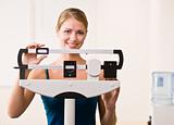 Woman weighing herself on scales in health club