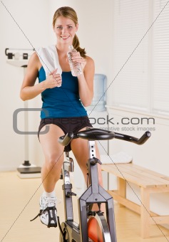 Woman riding stationary bicycle in health club