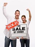 Couple cheering and holding for sale sign