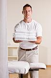 Massage therapist holding stack of towels