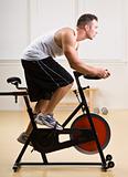 Man riding stationary bicycle in health club