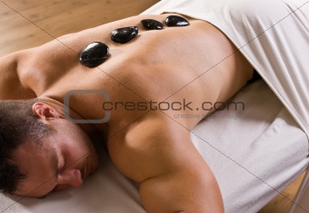 Man receiving hot stone therapy massage