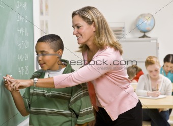 Teacher helping student at blackboard
