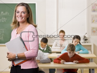 Teacher standing with notebook in classroom