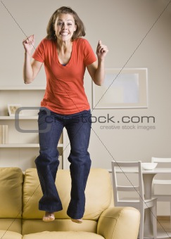 Teenage girl jumping on sofa
