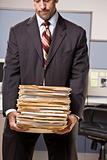 Businessman carrying stack of file folders