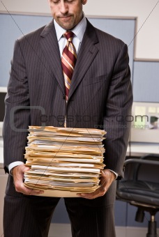 Businessman carrying stack of file folders
