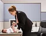 Businesswoman changing babyÕs diaper at desk