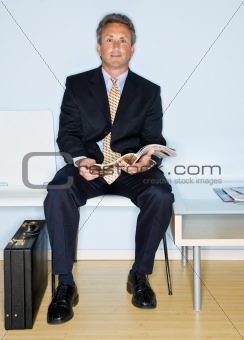 Businessman reading magazine in waiting room