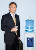 Businessman drinking water from water cooler