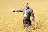 Farmer in suit standing in field of oats