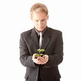 Man in suit holding smal plant in his hands 