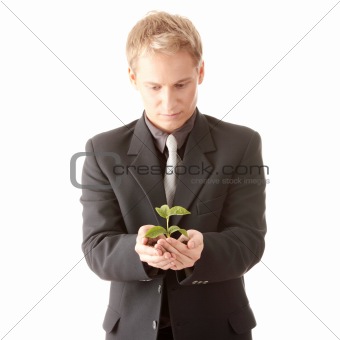 Man in suit holding smal plant in his hands 