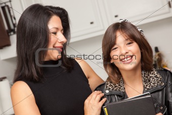 Attractive Hispanic Proud Mom with Her Pretty Schoolgirl Daughter in the Kitchen.