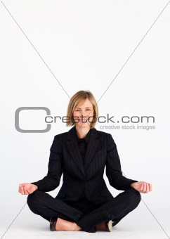 Businesswoman meditating on the floor and smiling at the camera