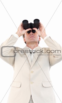 Serious businessman looking through binoculars in front of the camera