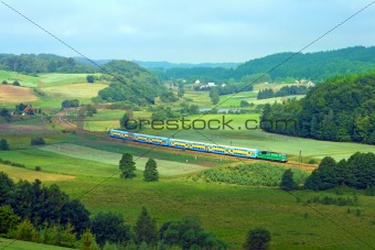 Landscape with a railway line, train, lake and forests