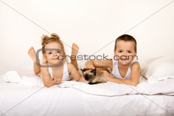 Kids with their kitten on the bed