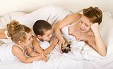 Familiy playing with a little kitten laying in bed