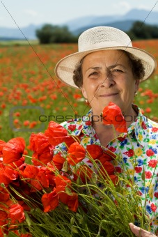Senior woman picking flowers on the poppy field
