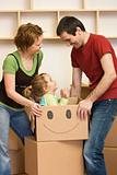 Happy couple with a kid unpacking in a new home