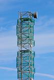 Telecommunications mast set against blue sky and small clouds