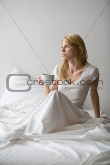 Woman sitting in bed holding a cup