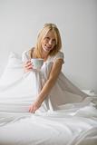 Woman Sitting in Bed With a Cup of Coffee