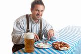 Bavarian Guy wearing leather trousers (lederhose) having meal at
