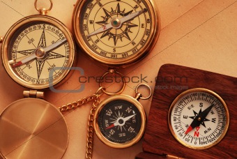 Four antique compasses over old background