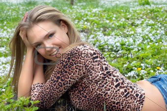 Cheerful girl on the green flowered meadow