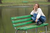 Girl sitting on the bench in the park with lake