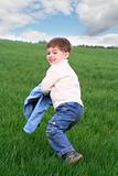 The cheerful boy on a background of a green grass and the sky