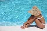 Woman in hat relaxing beside the pool