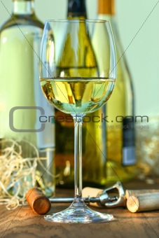 Glass of white wine with bottles