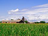 Old barn in the middle of a green field against clouds