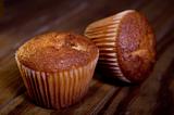 Two muffins on wooden table.