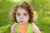 Little girl drinking juice from an orange brik