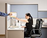 Businesswoman multi-tasking at desk in cubicle