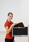 Businesswoman putting file in file cabinet
