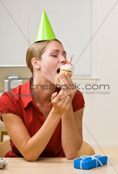 Businesswoman eating birthday cupcake