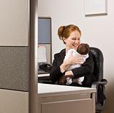 Businesswoman holding baby at desk