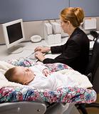 Businesswoman working with baby at desk