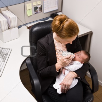 Businesswoman feeding baby at desk