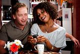 Mixed race couple in coffee house with cell phone