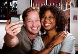Mixed race couple in coffee house with taking picture cell phone