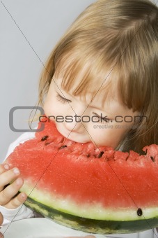 Little girl holds a slice of the watermelon and eats his