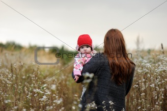 Young mother walking away holding her baby