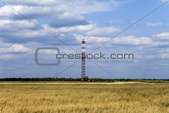 communications tower on field with cloudy sky background