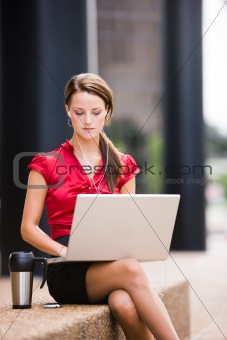 Woman taking a break with her coffee, mp3 player, and laptop